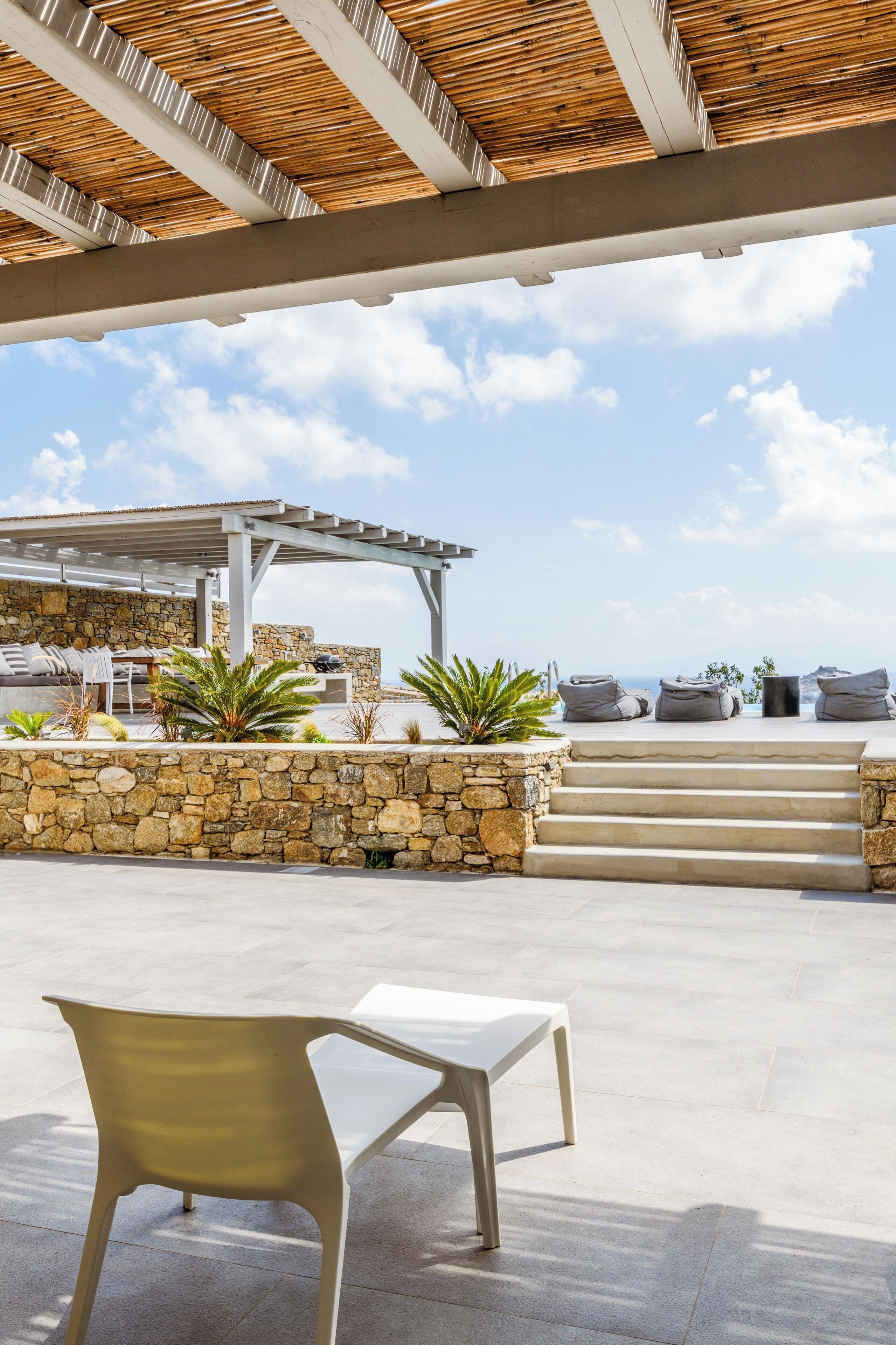 An outdoor seating area with stone walls, a pergola, and a view of the sea.