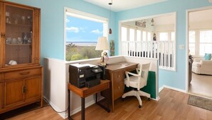 Une pièce comprenant un bureau, une chaise et offrant une vue sur l’extérieur.