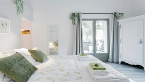 A bedroom with a bed, pillows, a mirror, a door, and a view of the outdoors. - TRANQUIL RETREAT: DISCOVER PICTURESQUE COUNTRYSIDE FARMHOUSE WITH POOL (Ménerbes)