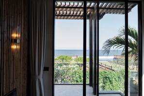 A room with a view of the ocean through large glass doors. - Ketewel Beach Villas & Spa (Batubulan)