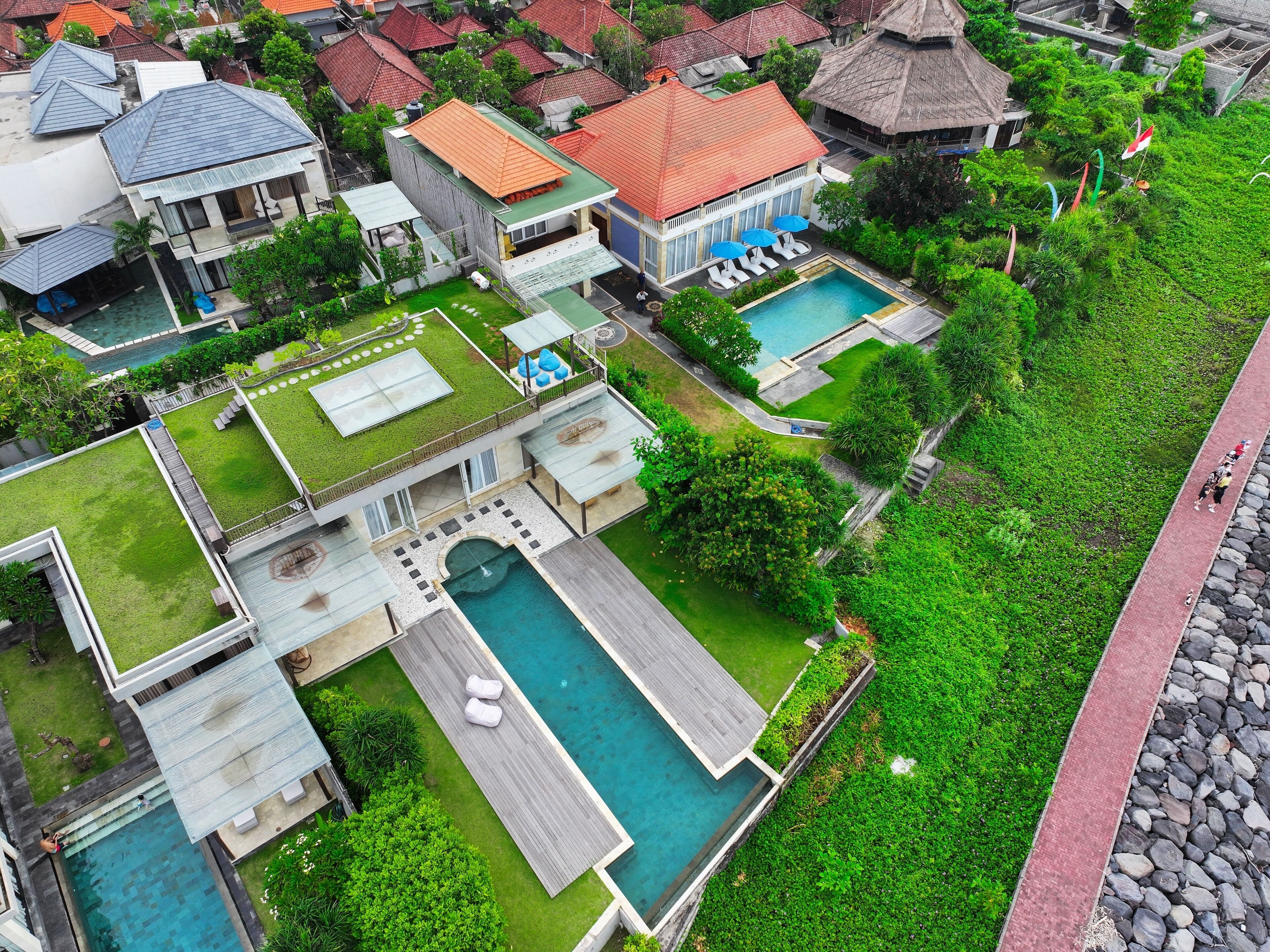 Vista aérea de una zona residencial con varias casas, una piscina y un jardín bien cuidado.