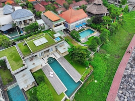 Vista aérea de una zona residencial con varias casas, una piscina y un jardín bien cuidado.
