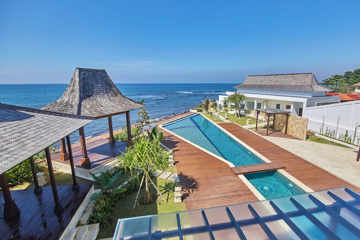 A resort with a swimming pool, wooden deck, and ocean view.