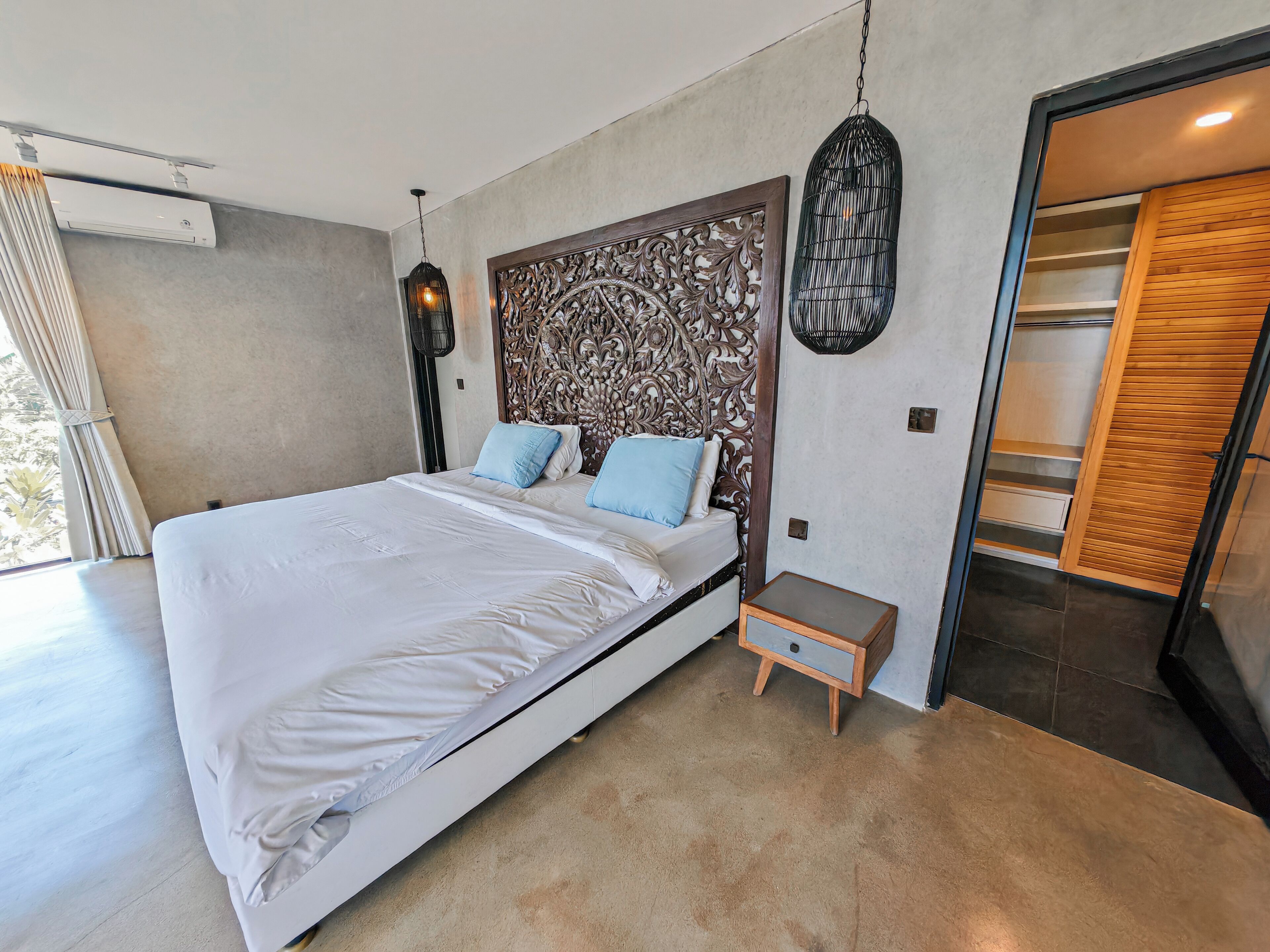 A modern bedroom with a large bed, a decorative headboard, a small bedside table, and a built-in wardrobe.