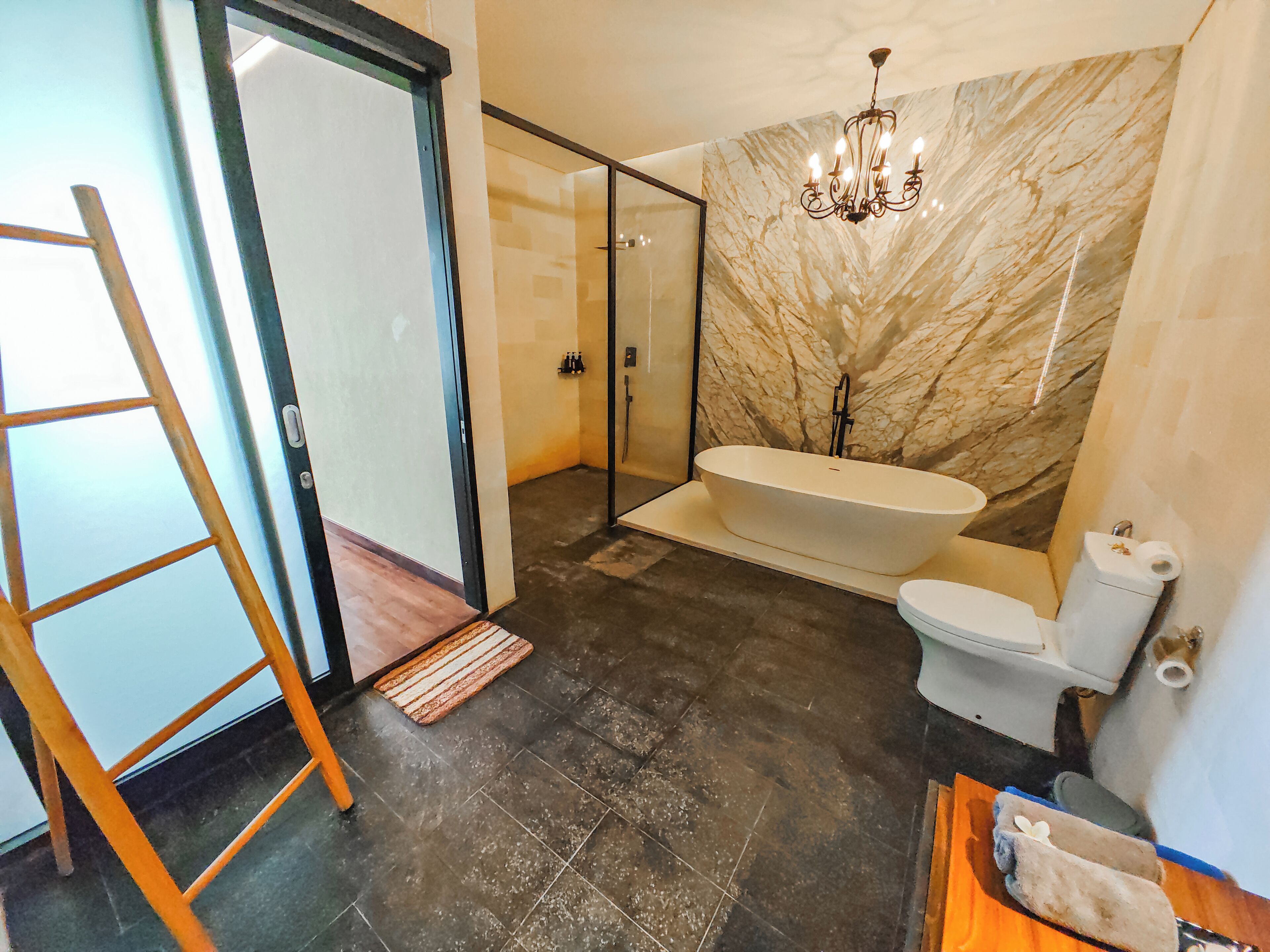 Un baño moderno con una bañera independiente, cabina de ducha de vidrio y pared de mármol.