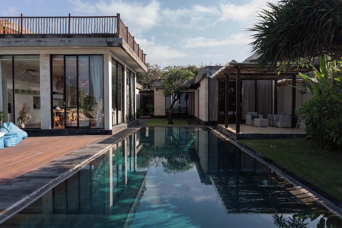 Una casa moderna con piscina, puertas de cristal y terraza de madera.