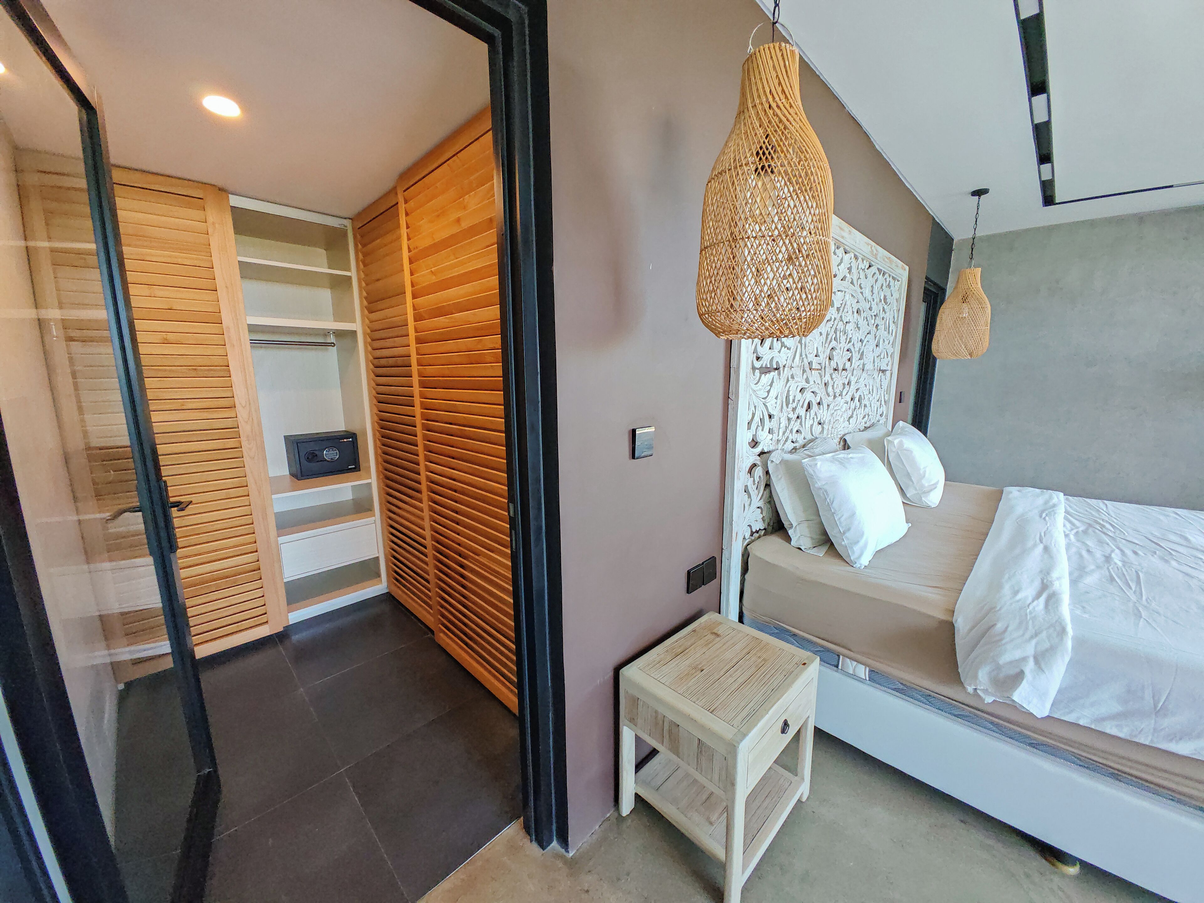 A bedroom with a bed, bedside table, and a wardrobe with a mirror.