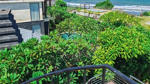 En ejendom ved kysten med havudsigt, swimmingpool og frodig vegetation.