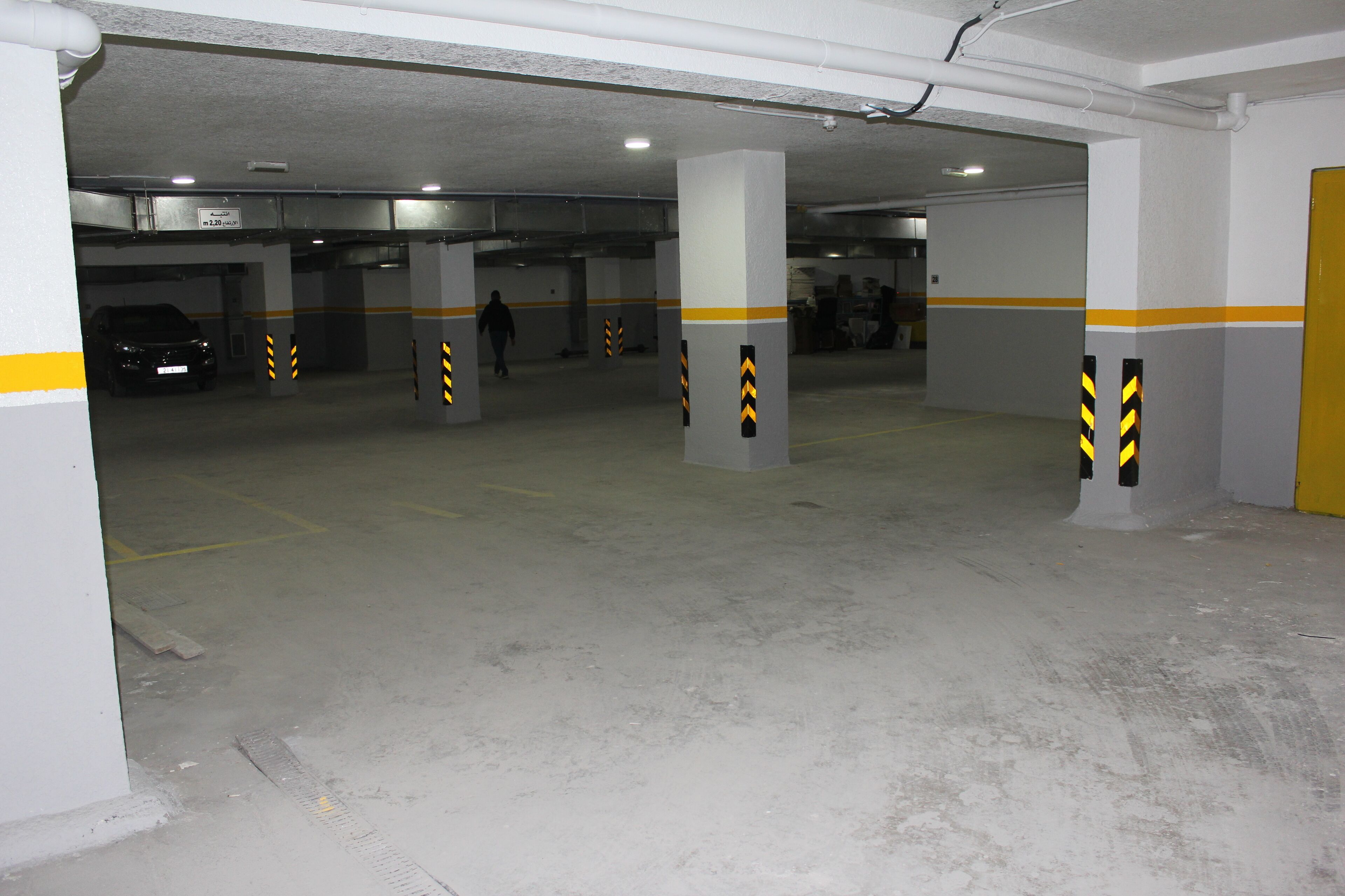 An underground parking garage with concrete pillars and yellow stripes.