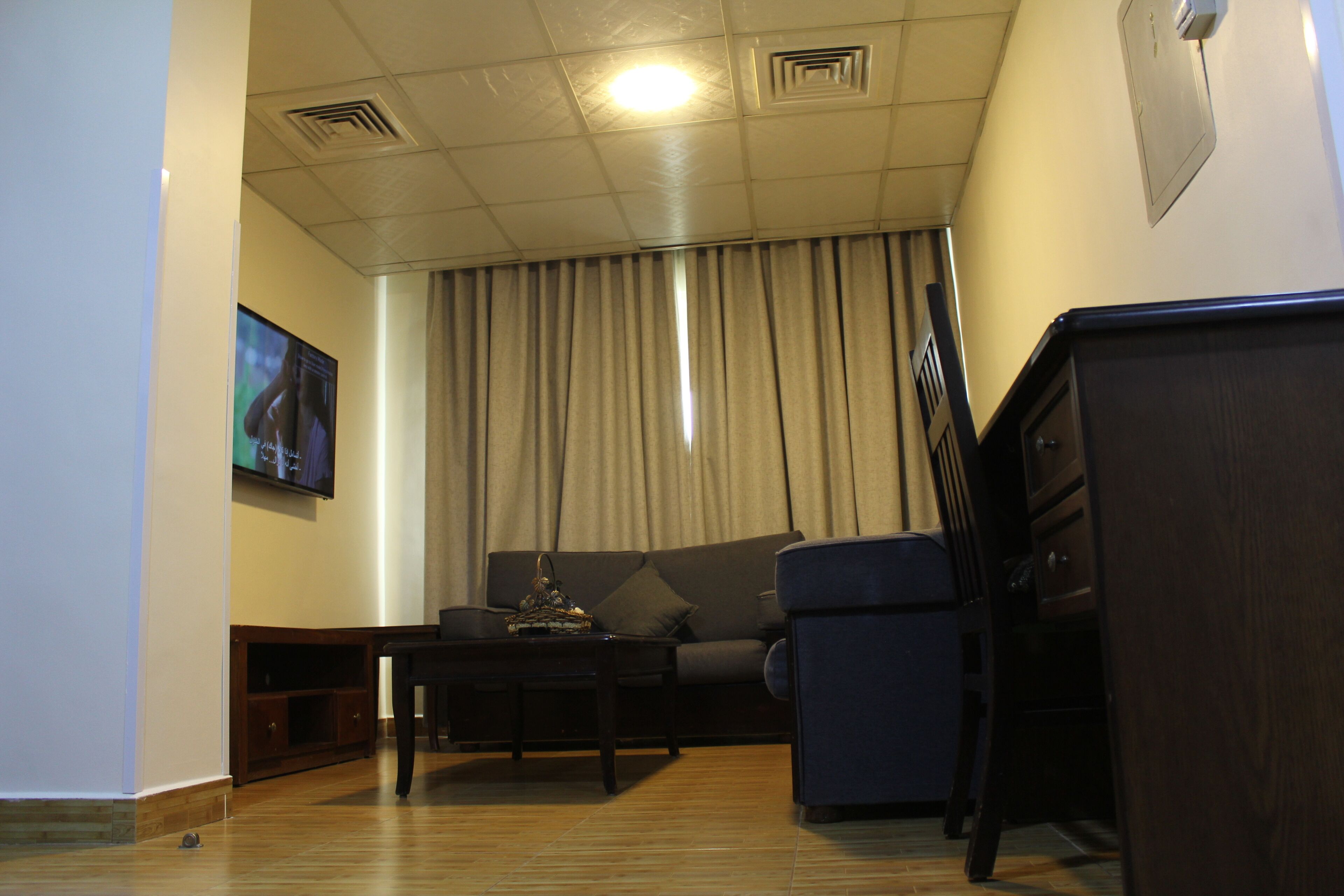 Ein Wohnzimmer mit einer Couch, einem Couchtisch und einem an der Wand befestigten Fernseher.
