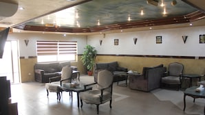 A spacious lobby with multiple seating areas, including sofas and armchairs, arranged around a central coffee table. - Al Ahfad Hotel Apartments  (Amman)