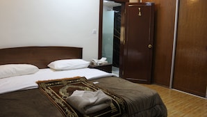 A neatly made bed with white and brown bedding, a wooden headboard, and a brown patterned throw. - Al Ahfad Hotel Apartments  (Amman)