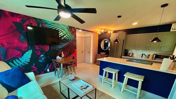 A modern living room with a sofa, coffee table, and a kitchen area with a counter and stools. - MiamiVice Las Olas Near Beach & Park with Fire Pit! (Fort Lauderdale)
