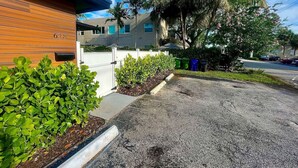 A building with a wooden facade, a parking lot, and a row of green shrubs. - MiamiVice Las Olas Near Beach & Park with Fire Pit! (Fort Lauderdale)