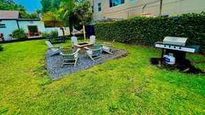 A backyard with a grill, outdoor seating, and a building in the background. - MiamiVice Las Olas Near Beach & Park with Fire Pit! (Fort Lauderdale)
