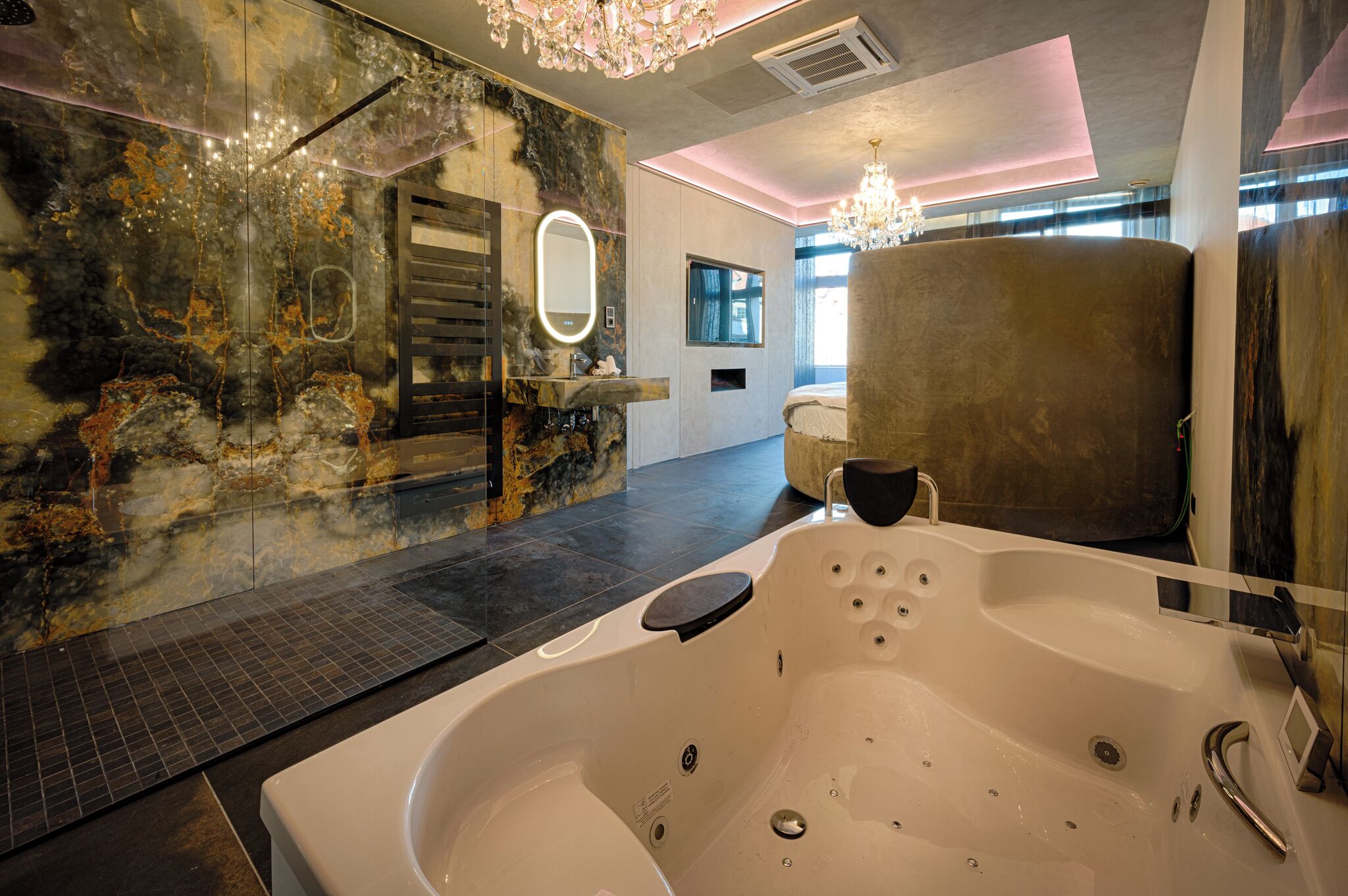 A modern bathroom with a large bathtub, a glass shower enclosure, and a marble wall.