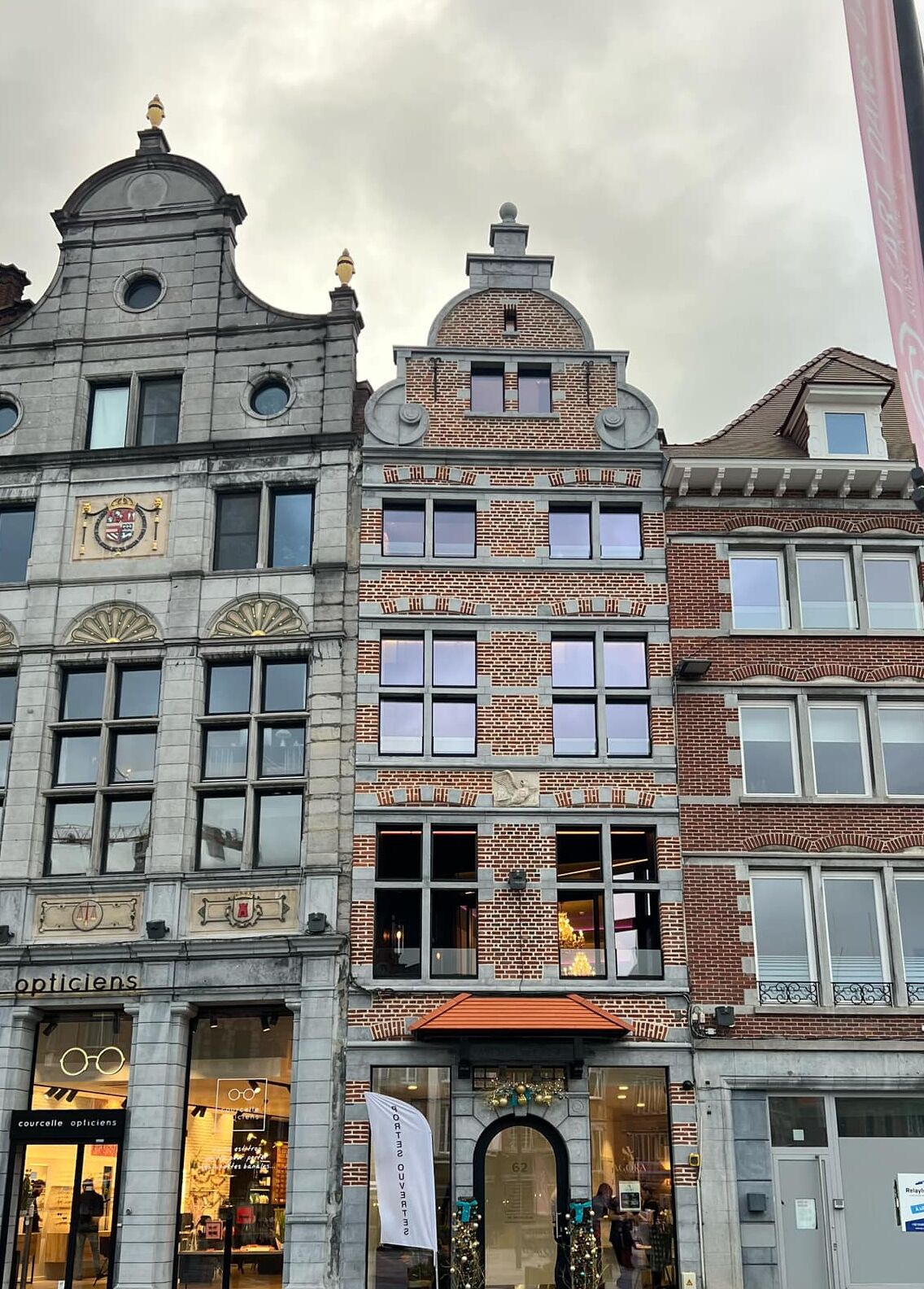 Ein historisches Gebäude mit einem markanten Glockenturm, zahlreichen Fenstern und einem Schaufenster, auf dem ein Schild mit der Aufschrift „opticians“ zu sehen ist.
