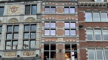 Ein historisches Gebäude mit einem markanten Glockenturm, zahlreichen Fenstern und einem Schaufenster, auf dem ein Schild mit der Aufschrift „opticians“ zu sehen ist.