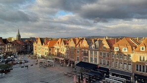 A historic European town square with traditional architecture, a prominent church spire, and outdoor seating areas. - Agora Wellness suites (Tournai)