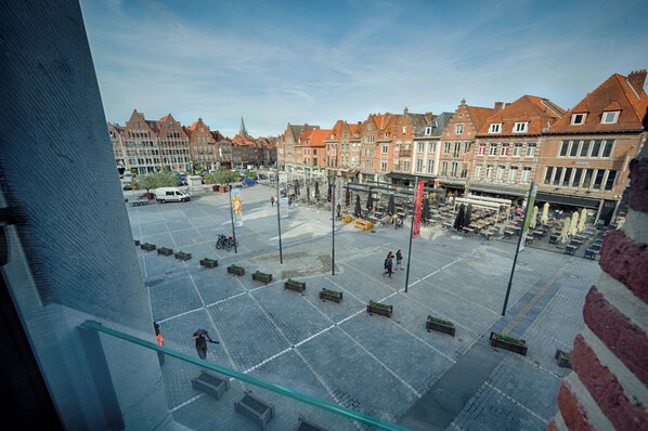A spacious square with benches and tables, surrounded by historic buildings with red roofs and a clear sky. - Agora Wellness suites (Tournai)