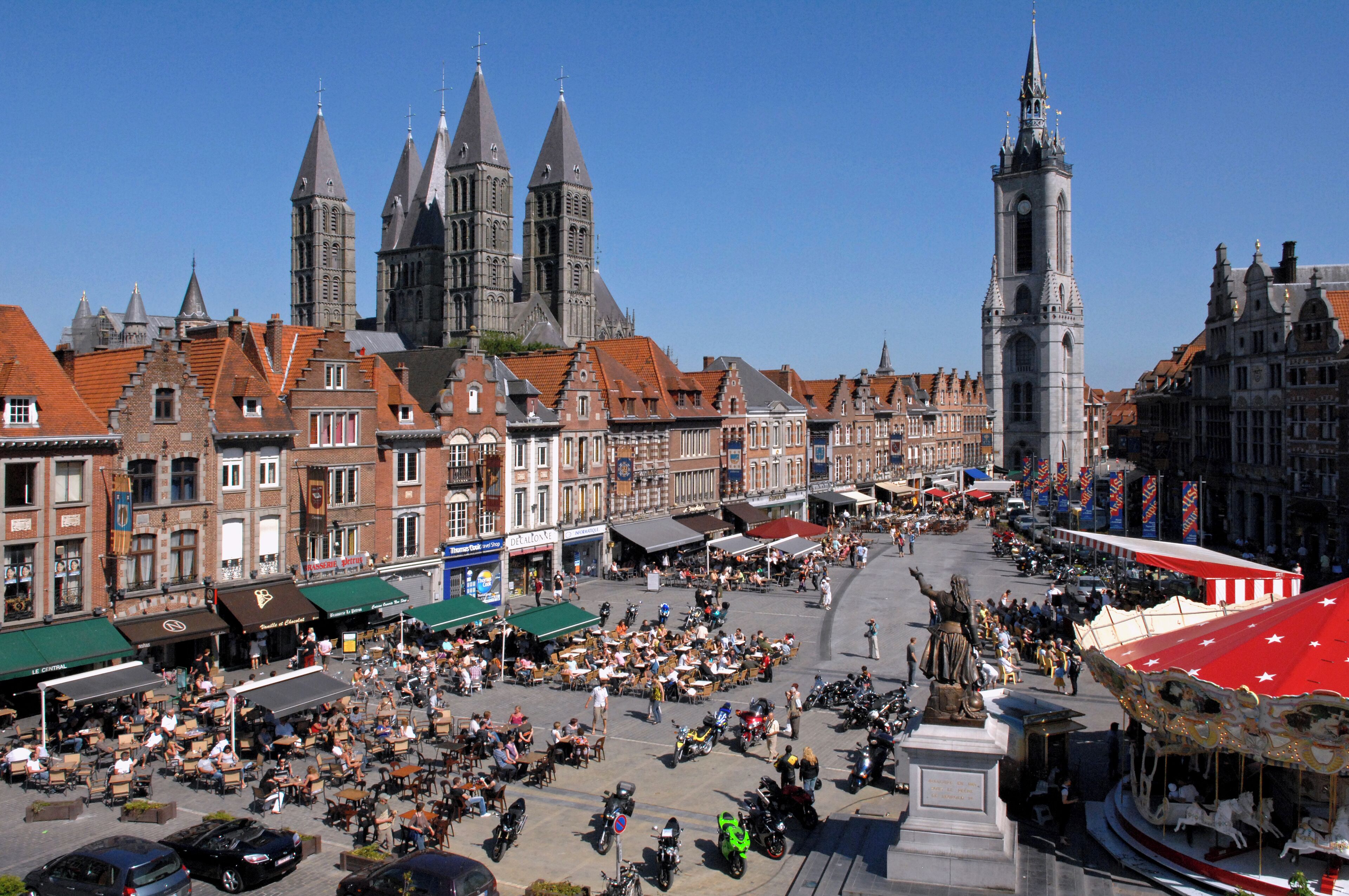 A bustling square with historic buildings, a prominent church, and a tall clock tower.