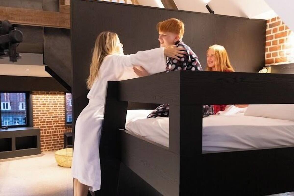 A bunk bed room with a TV, brick wall, and skylight.