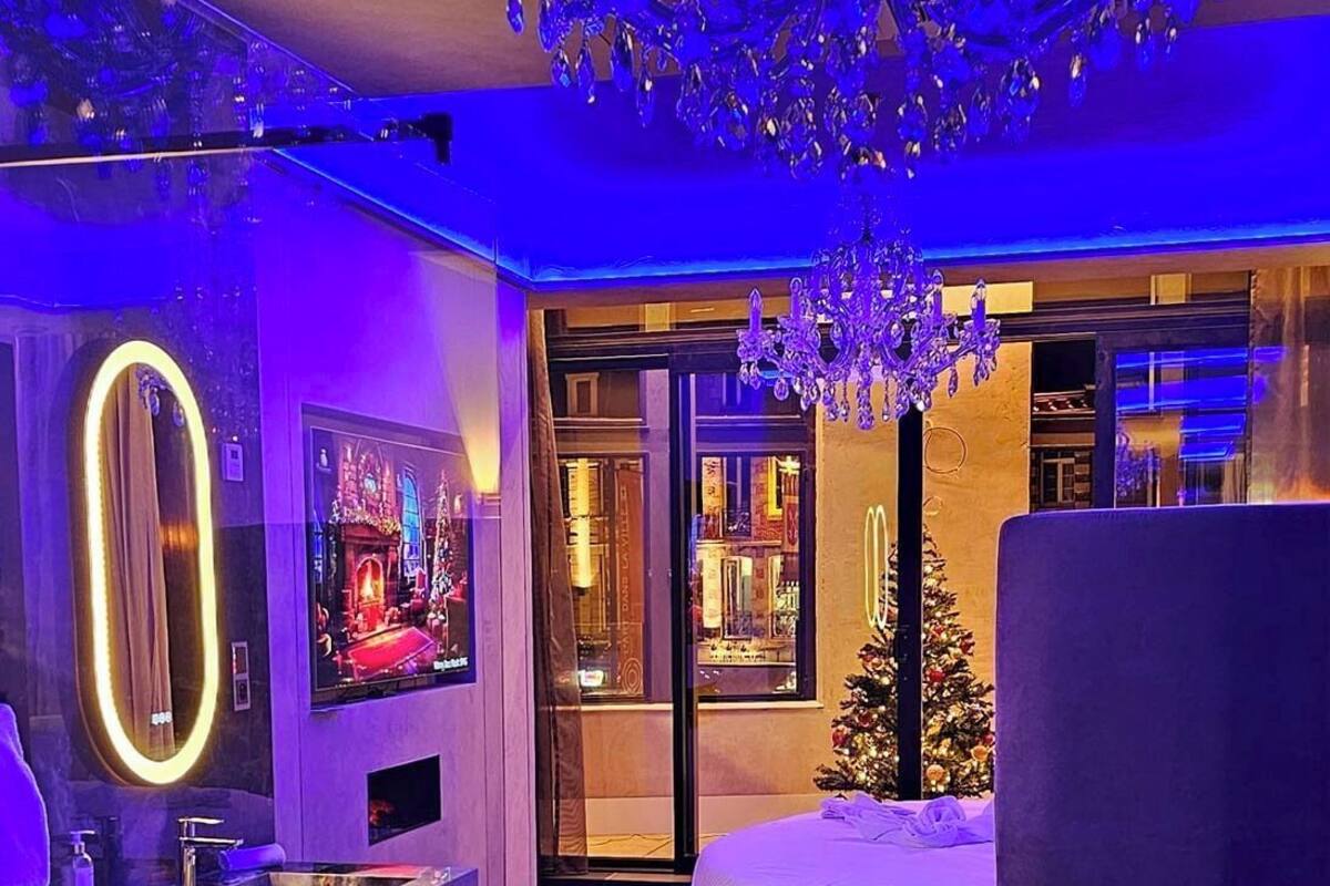 A modern living room with a large chandelier, a fireplace, and a Christmas tree.