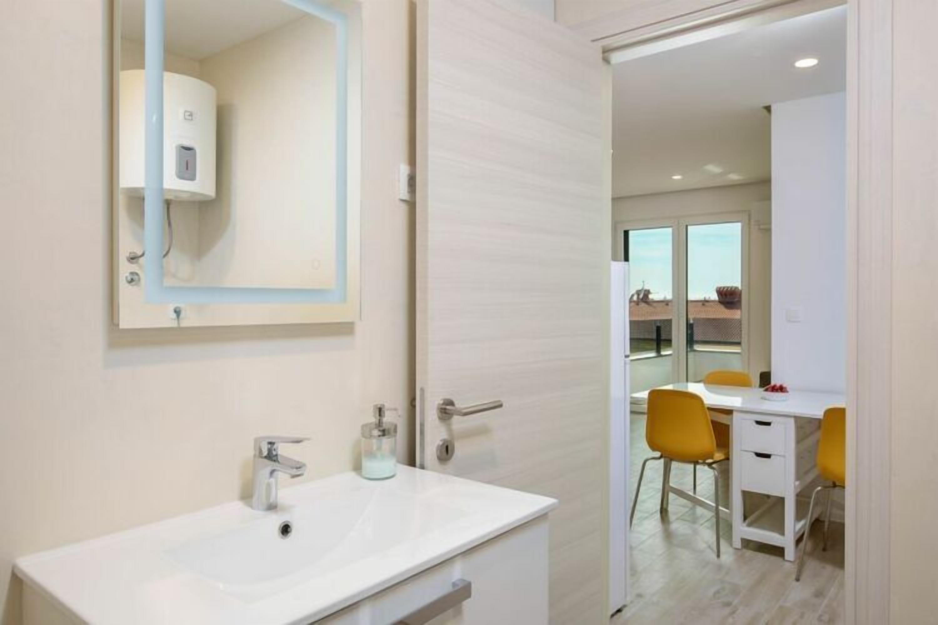 A modern bathroom with a white sink, a mirror, and a towel rack.