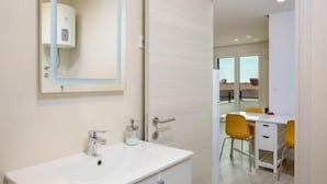 Une salle de bain moderne avec un lavabo blanc, un miroir et un porte-serviettes.