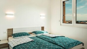 Une chambre avec deux lits, chacun agrémenté de draps turquoise et blancs, d’une tête de lit en bois et de deux lampes fixées au mur.