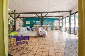 A spacious indoor area with a tiled floor, a reception desk, a seating area with a sofa and chairs, and a large window providing natural light. - L'Eau Vive (Lescheraines)