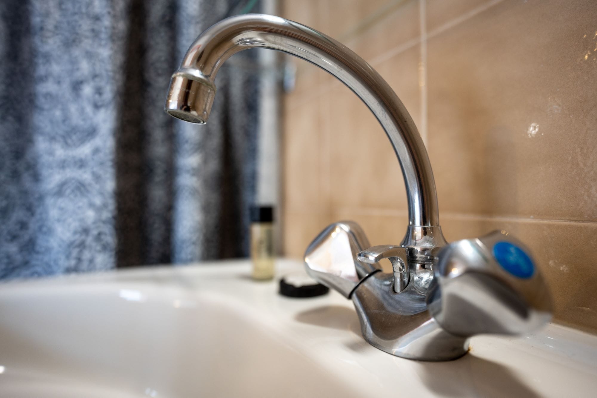 A bathroom sink with a chrome faucet, a soap dispenser, and a bottle of liquid soap.