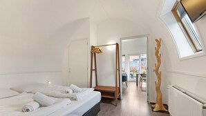 Een moderne hotelkamer met een groot bed, een houten baldakijnbed, een radiator en uitzicht op het buitengebied.