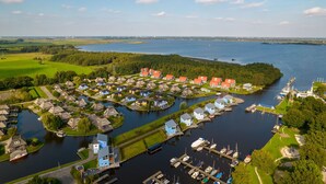Een vogelperspectief van een rivierdorp met huizen, steigers en boten.