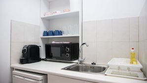 A compact kitchenette with a microwave, toaster, and sink. - Spacious apartment nearby restaurants, cafes and 2 minutes walk from the metro!
 (Athens)