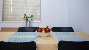A dining table with a bowl of fruit, two black chairs, and a vase with flowers. - Spacious apartment nearby restaurants, cafes and 2 minutes walk from the metro!
 (Athens)