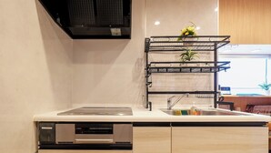 A modern kitchen with a dishwasher, a sink, and a built-in stove. There is a black metal rack with plants on top of the wall above the sink.