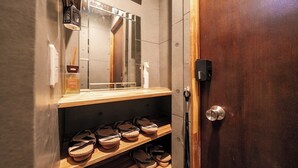 Un baño con un estante de madera que contiene zapatos, un espejo y artículos de aseo.