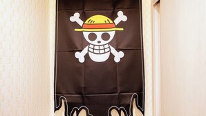 Un banner negro con un diseño de calavera y tibias cruzadas, que incluye un sombrero de paja.