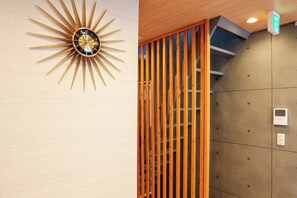 A sunburst wall clock, a wooden slat partition, and a control panel on a wall. - Itabashi Ekimae Store Diamond Yuu (Tokyo)