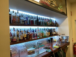 A bar area with shelves of liquor bottles, a sink, and a fire extinguisher. - Grand Hotel Bega (Bega)