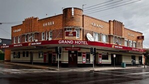 Un edificio de ladrillo con el letrero 'GRAND HOTEL', ubicado en una esquina y con entrada visible.