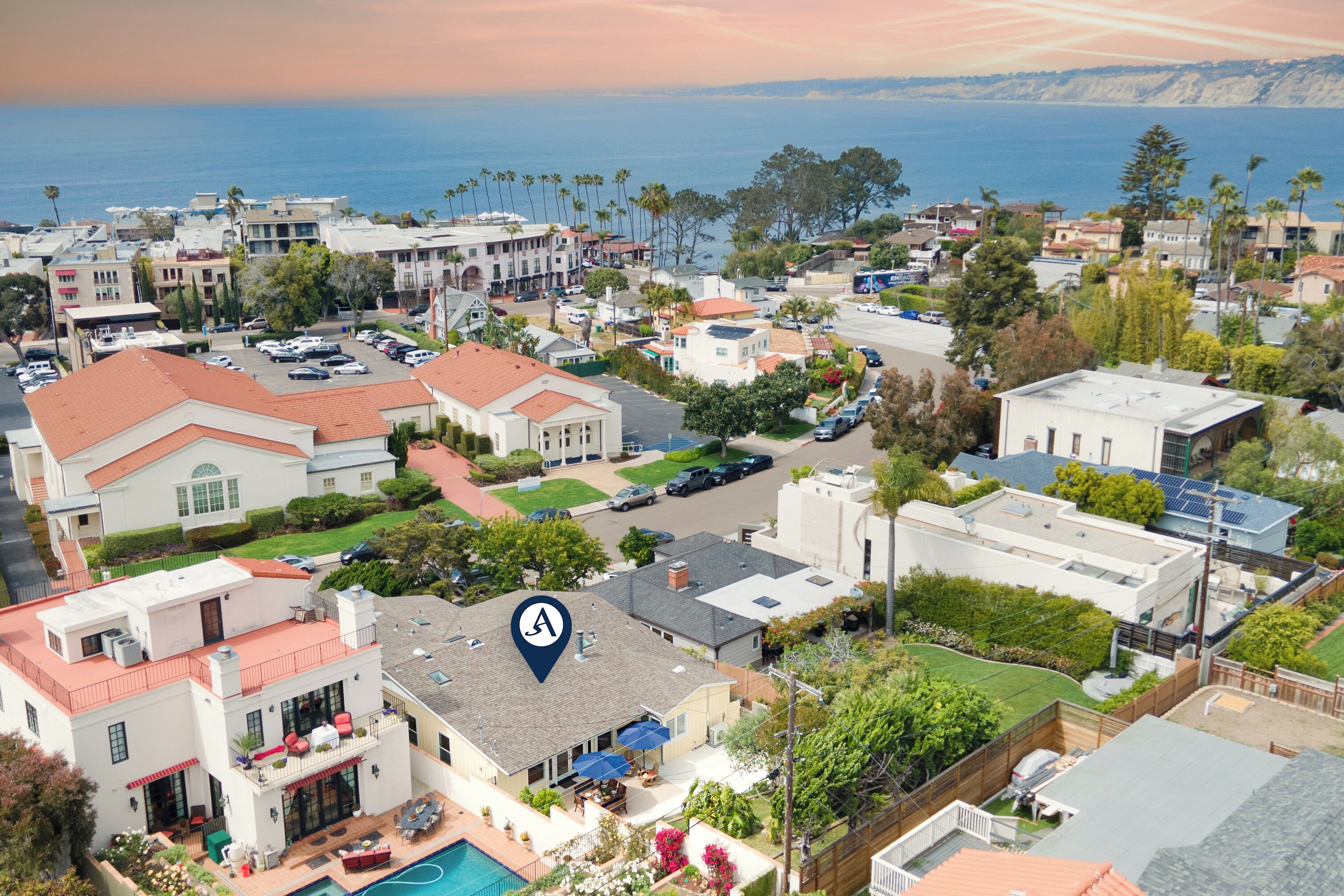 A residential area with houses, a swimming pool, and a view of the ocean.