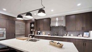 A modern kitchen with dark wood cabinets, a large island with a sink, and pendant lighting. - Frontgate 211 - 3 Bedroom Residence (Avon)