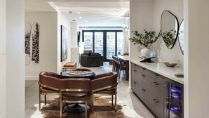 A modern kitchen with a dining area, featuring a central island, dark brown leather chairs, and a cowhide rug. - Frontgate 211 - 3 Bedroom Residence (Avon)