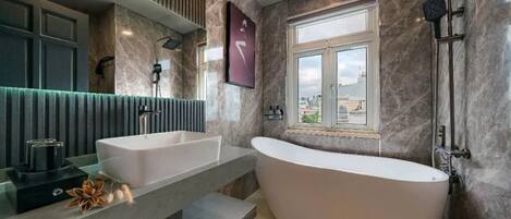 Une salle de bain moderne avec une baignoire sur pieds, deux vasques et une grande fenêtre offrant une vue sur la ville.