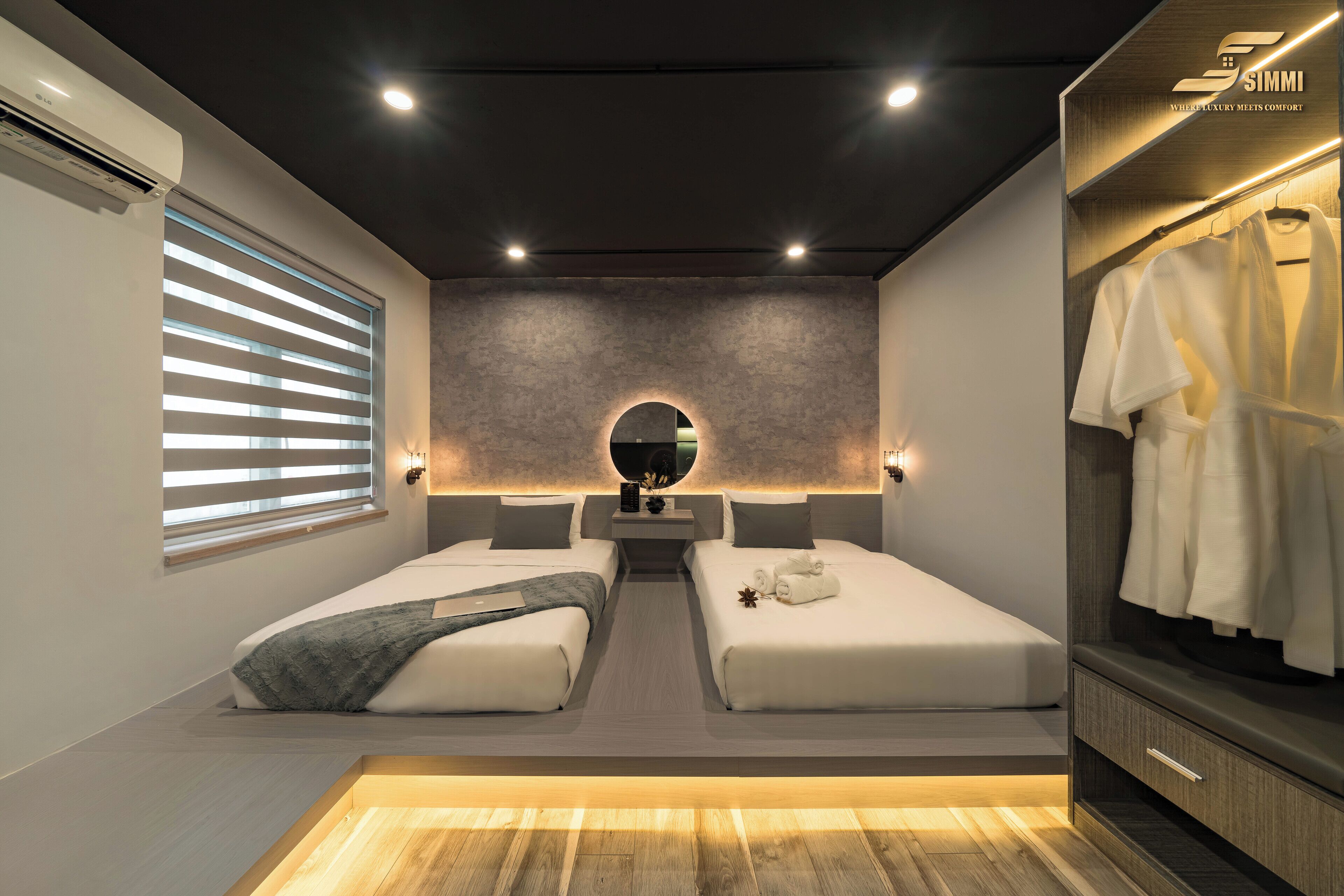 Une chambre moderne avec deux lits, une coiffeuse avec un miroir et un dressing.