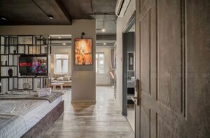 Een moderne woonkamer met een groot bed, een open haard en een tv aan de muur waarop Netflix wordt afgespeeld.
