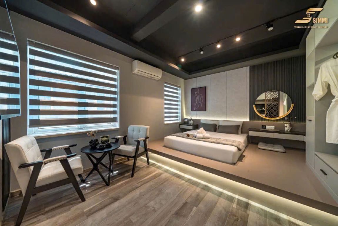 A modern hotel room with a sofa, a chair, a small table, and a bed.