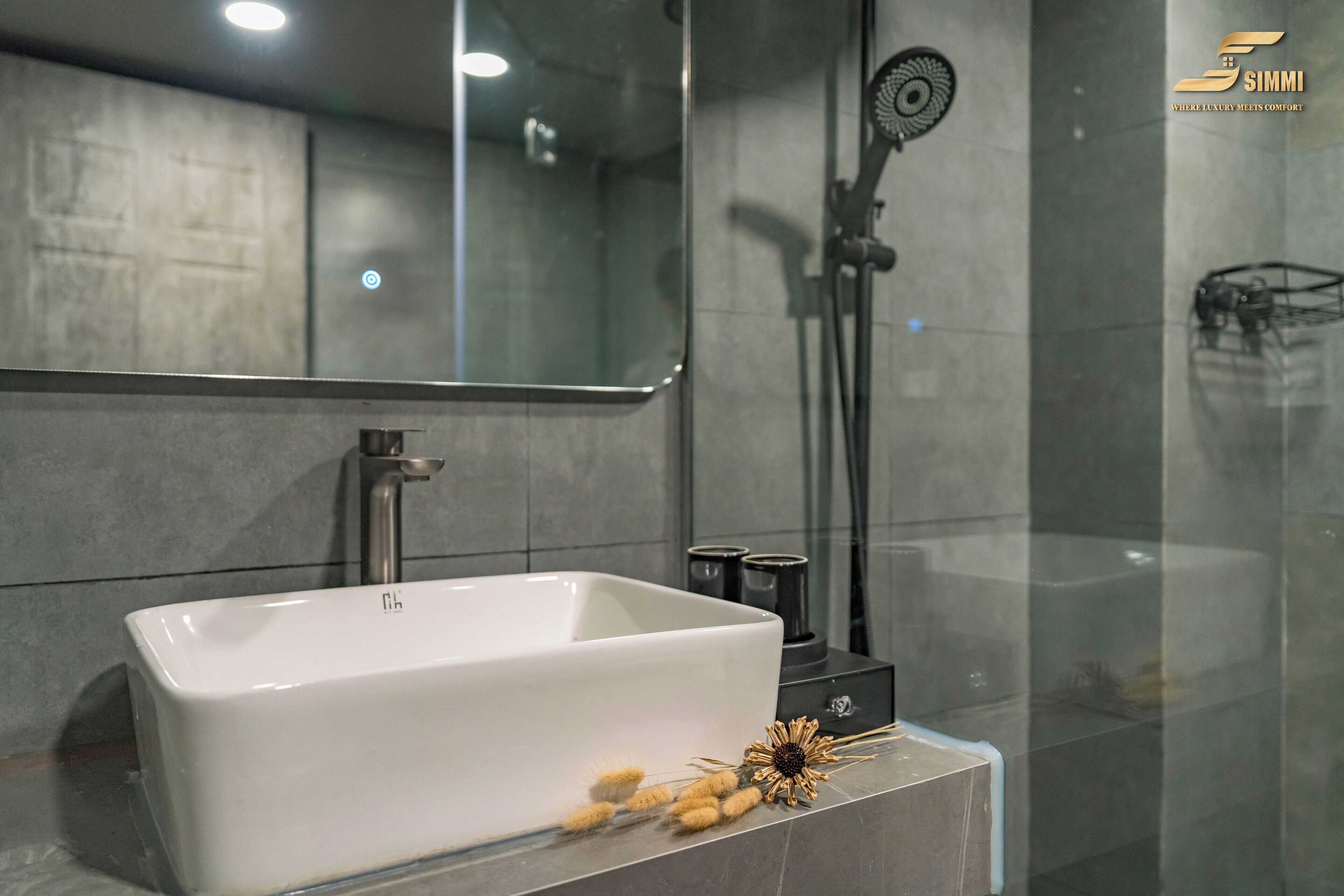 A modern bathroom with a rectangular white sink, a mirror above it, and a glass shower enclosure.